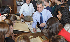 Faculty and students engaged around table with historical books